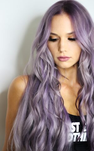 purple haired woman in black top leaning on wall